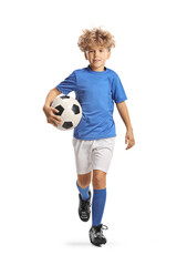 Full length portrait of a boy in a football kit running and carrying a ball