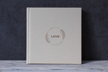 wedding or family photoalbum isolated on gray. Stylishphoto book. beige photo album with  cover  with a word love on gray background with copy space for text. pastel photo book close up portrait.  - obrazy, fototapety, plakaty