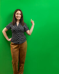 Woman pointing at an green cardboard empty background - copy space for text.