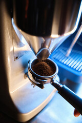 Barista using grinding machine to prepare espresso powder for making coffee