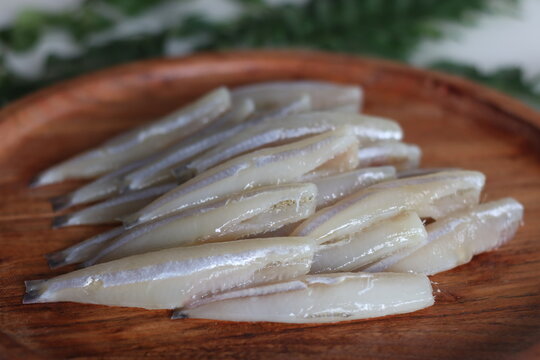 Freshly cut and cleaned anchovy fish presented on a rustic wooden tray
