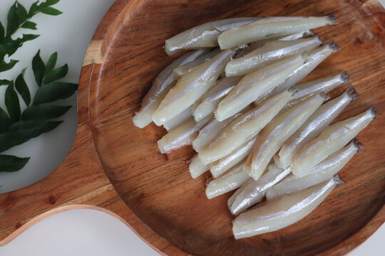 Freshly cut and cleaned anchovy fish presented on a rustic wooden tray