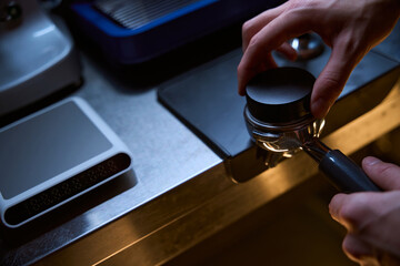 Barista holding tamper and portafilter with coffee for making coffee espresso