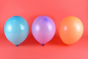 Set of colorful festive matte balloons on coral background. Décor for birthday, anniversary, celebration or other events. Children party decorations