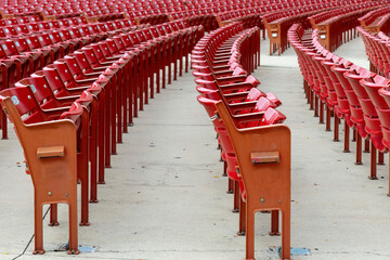 Low angle view over what seems as endless curved rows of red plastic seats in a stadium or arena...