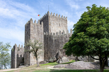 Fototapeta na wymiar Guimaraes Castle in Guimaraes, Portugal, a hilltop Romanesque castle, founded in the 1000s and birthplace of Afonso Henriques against a clear blue sky