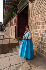 Female Asian tourist wearing traditional hanbok costume walking tours Gyeongbokguk Palace, South Korea.