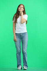 A woman, full-length, on a green background, tired