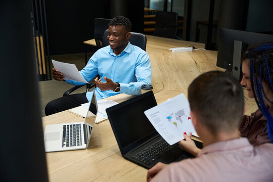 African American man and colleagues looking at global trading transfers data