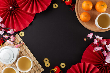 Creative concept for the chinese New Year tea ritual. Top view shot of tea crockery, tangerines, traditional chinese decor on black background with advert area