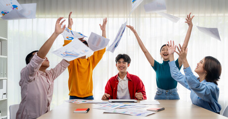 Excited and happy startup company employee celebrate and throw paper in the air after make...