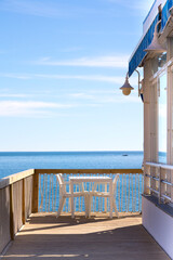 Chiringuito o restaurante de playa con sus mesas ,sillas y sombrilla mirando al mar mediterráneo con el horizonte al fondo y un día luminoso de sol