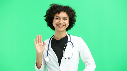 Female doctor, close-up, on a green background, waving her hand