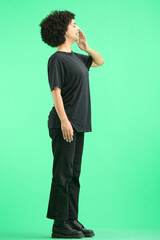 A woman, full-length, on a green background, yawns