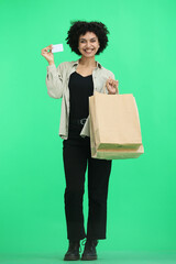 A woman, full-length, on a green background, with bags and a card