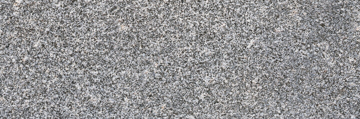 Granite texture. Natural gray granite with a grainy pattern. Stone background. Solid rough surface of rock. Durable construction and decoration material. Close-up.