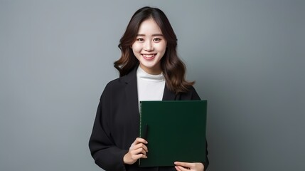 A young and beautiful lady is depicted frontally wearing a white shirt, black jeans, and a coat while holding a green book and pen on a white background.