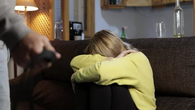 A man with a leather belt insults his family. Domestic violence. The husband oppresses his wife
