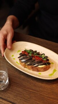 A restaurant guest holds a bruschetta. Close-up 