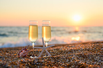 A romantic evening on the seashore for lovers. Two glasses of cold wine and shells against the backdrop of the sea and sunset.