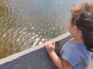 Little Brazilian girl watching the fountain waves in the wind
