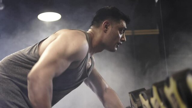 SingleOne Arm Dumbbell Rows, Male bodybuilder doing weight lifting workout at gym.