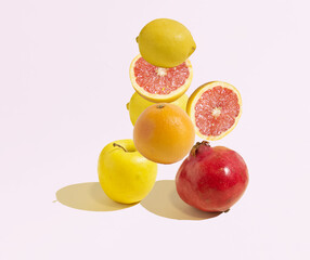 A pattern made of an orange, a pomegranate, an apple, a sliced grapefruit, and lemons 