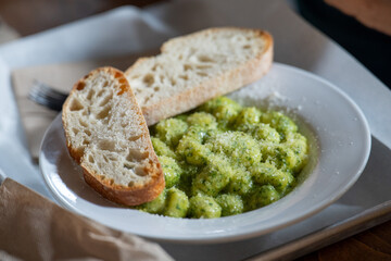delicious green pesto gnocchi at an italian restaurant with two pieces of toast