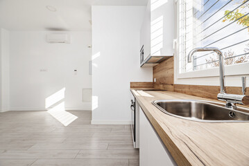 Fototapeta premium a kitchen under a window with a wooden countertop