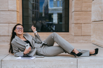 Smiling businesswoman with phone, sitting outdoors