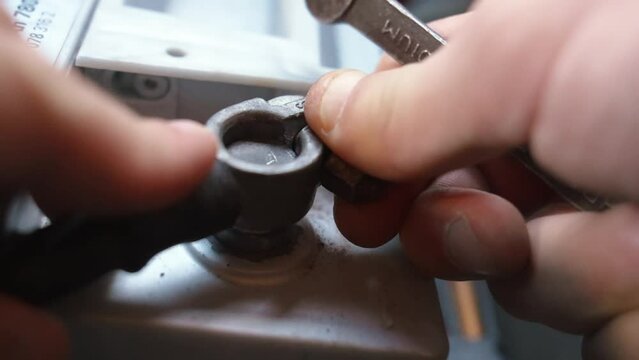 Disconnecting battery in car before parking for extended period of time. Disconnects car battery terminal. Mechanic hand holding car battery terminal after replacing new battery. Car maintenance