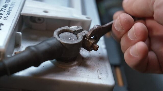 Disconnecting battery in car before parking for extended period of time. Disconnects car battery terminal. Mechanic hand holding car battery terminal after replacing new battery. Car maintenance