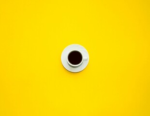 On a bright yellow background, a white cup with black coffee stands in the center.  Space for copy...