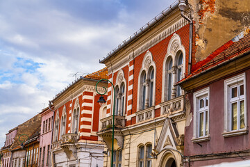 Red and White Building With Clock in Brasov, Romania. A vibrant red and white building adorned with...