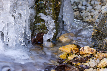 Icicles and ice formations in a garden with a water stone in cold winter