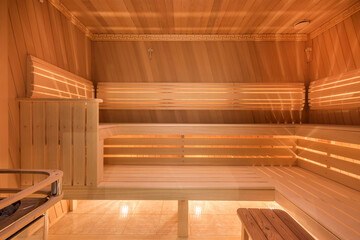 Comfortable benches with headrests in the interior of a traditional wooden sauna. A heater and a nice backlight.