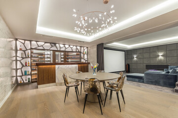 A luxurious living room with a table and a bar counter and a home cinema. - obrazy, fototapety, plakaty