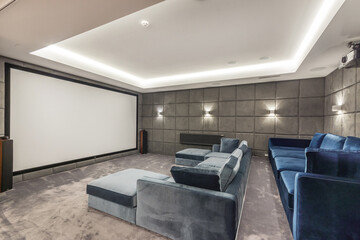 A private cinema in the house with a large screen and two blue sofas.
