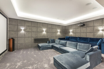 A spacious home theater room of a private house with comfortable blue sofas.