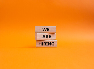 We are Hiring symbol. Concept words We are Hiring on wooden blocks. Beautiful orange background. Business and We are Hiring concept. Copy space.