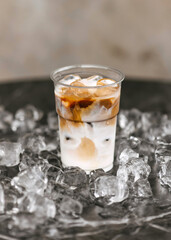 A cup of iced coffee swirls among scattered ice cubes.