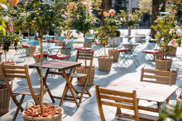 Fototapeta na wymiar Outdoor café with wooden tables and chairs surrounded by potted plants.