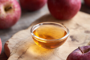 A bowl of apple cider vinegar with fresh apples