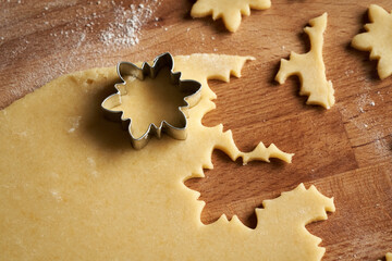 Cutting out star shapes from raw pastry dough to prepare Linzer Christmas cookies