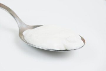 Sour cream or white sauce in a spoon on a white plate close-up
