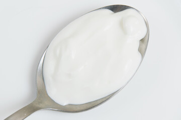 Sour cream or white sauce in a spoon on a white plate close-up