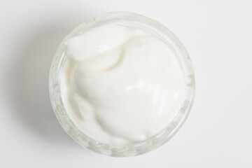 Sour cream in a glass saucer on a white background