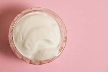 White sauce in a glass saucer on a pink background