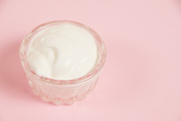 White sauce in a glass saucer on a pink background