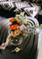 Bridal bouquet in glass vase on table with ribbon, near window.